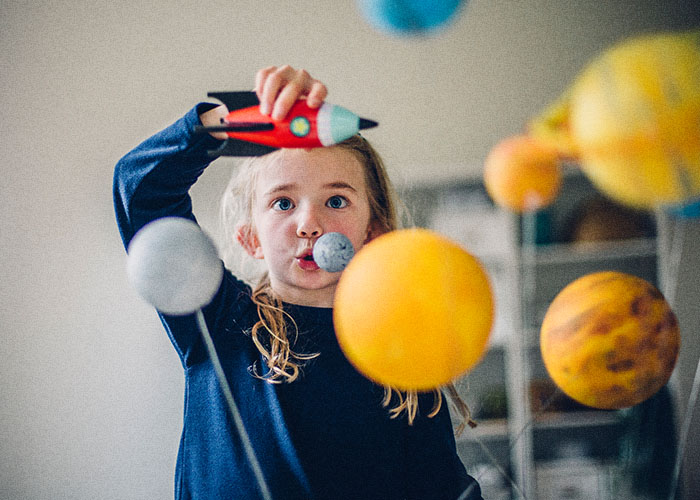 young girl playing with rocket and planets